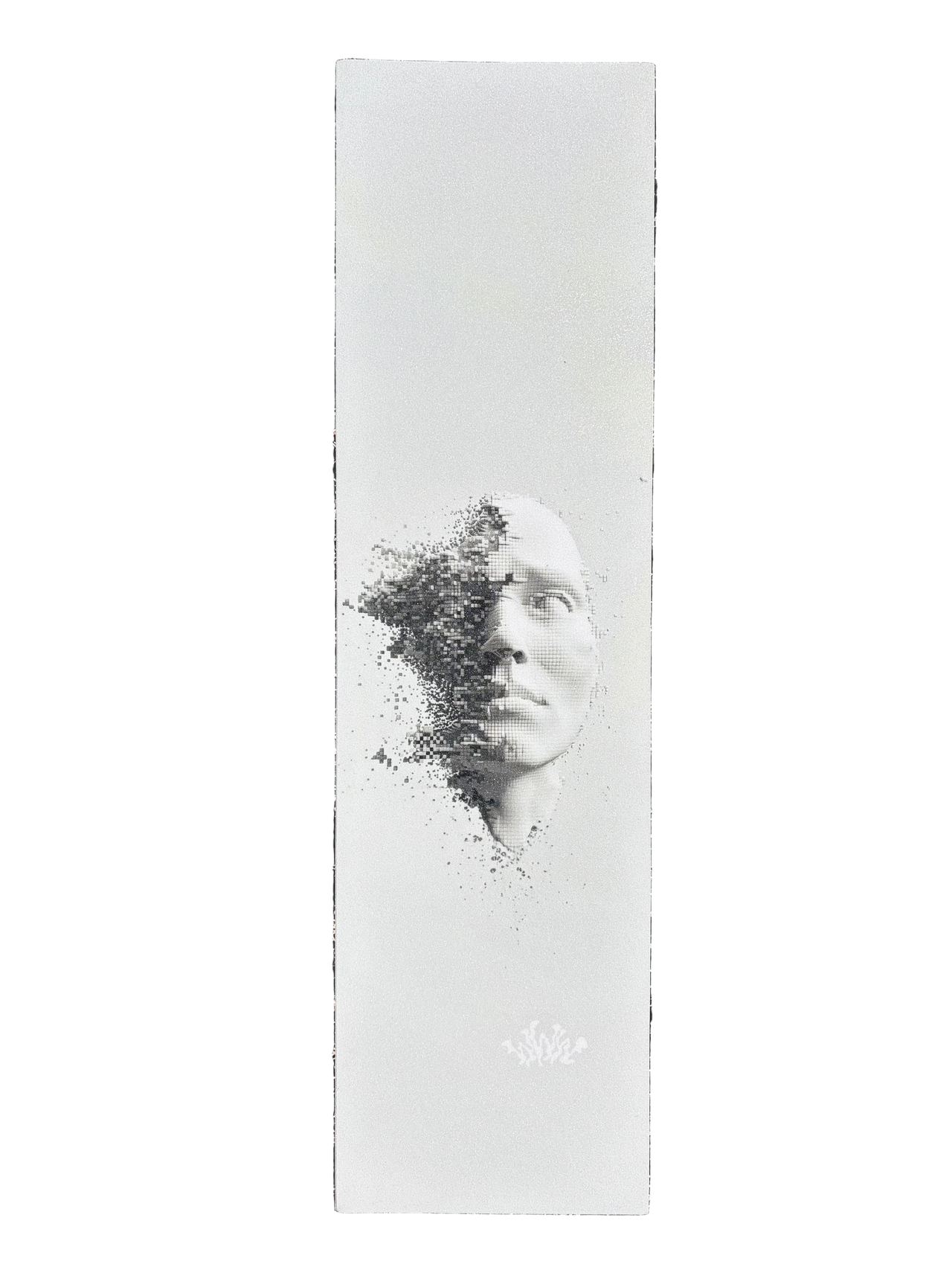 A tall white rectangular print or poster lies on dark asphalt. The artwork shows a grayscale portrait of a face with the left side dissolving into black speckles, and a small white logo near the bottom.